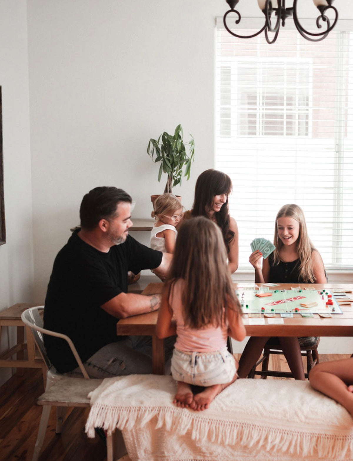 10 Family Activities You've Never Thought to Do. Family of five sit around a table and bond over playing board games together.