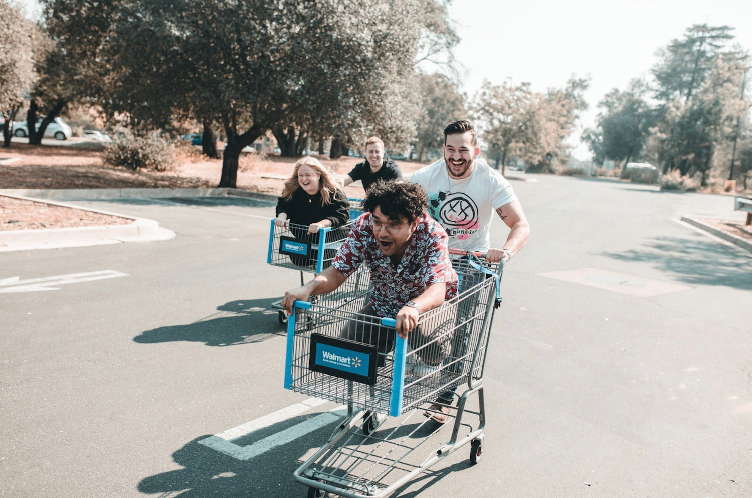Friends push each other in shopping carts as they race down the street for a fun summer activity.