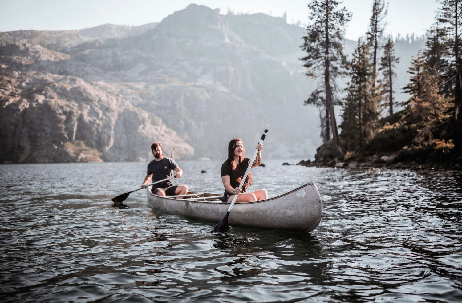 A couple canoeing together in a lake during their unforgettable summer.
