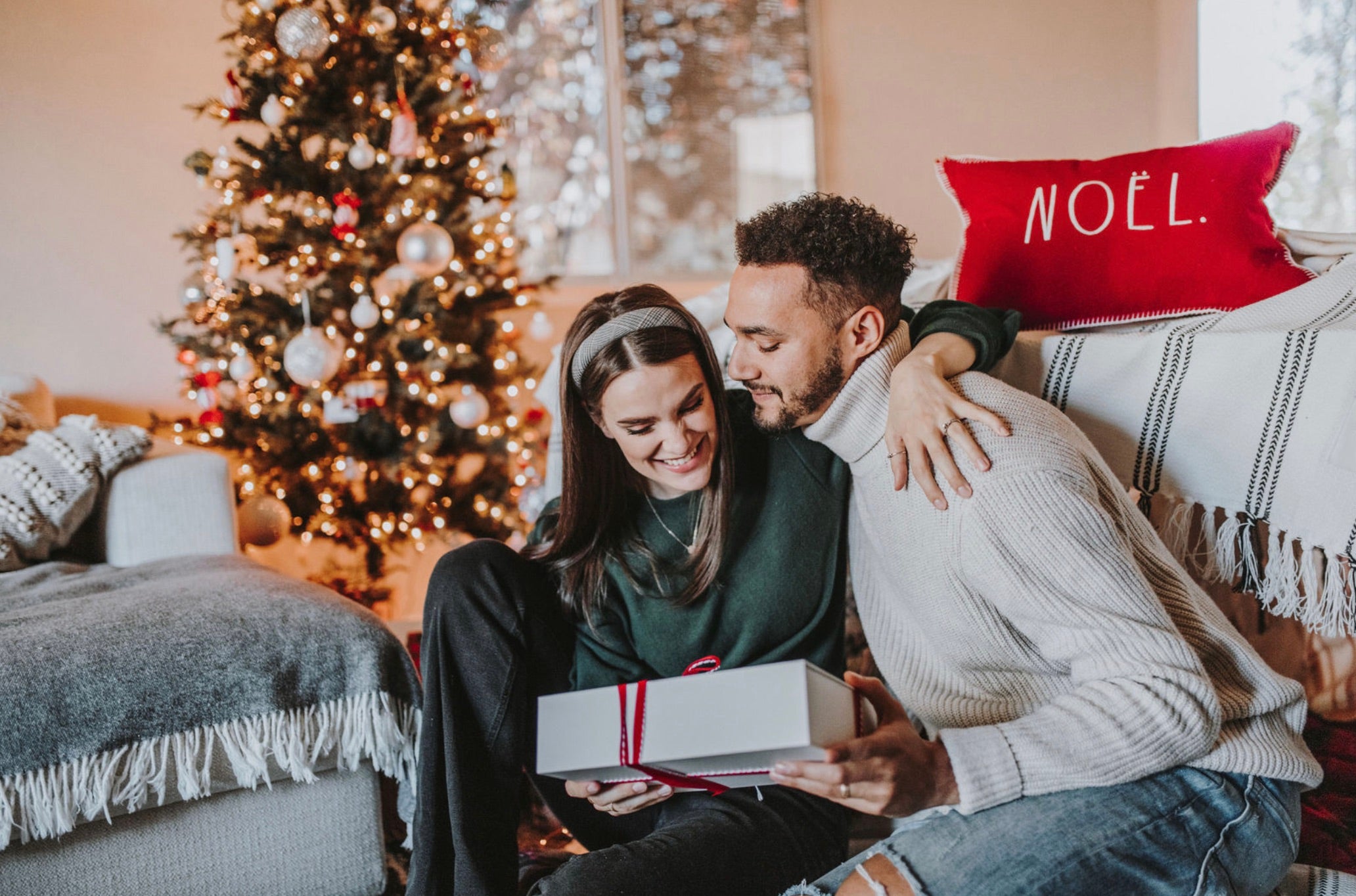Boyfriend and girlfriend open Christmas presents in their living room