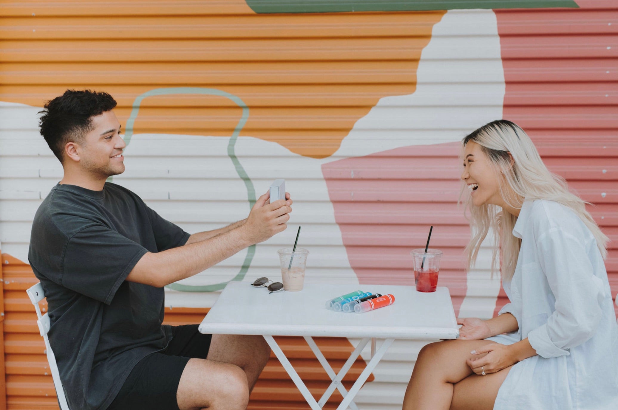 Couple share laughs from across the table during their cafe date; romantic gift for your wife