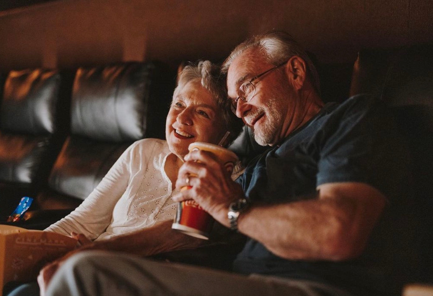 5 date ideas to celebrate national couple’s day: Elderly couple sharing smiles during their movie date.