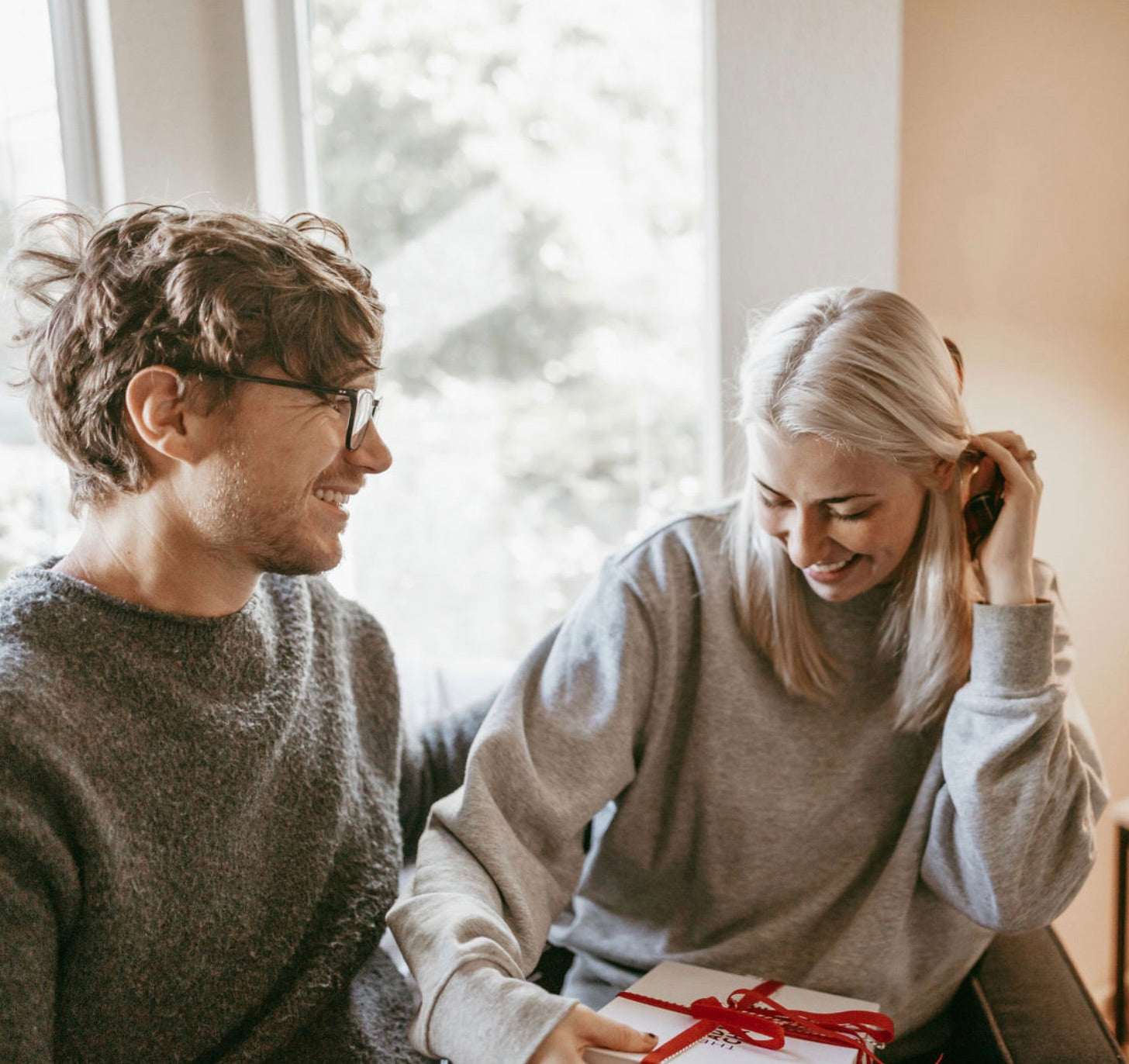 Bride smiles and tucks her hair as she receives a birthday gift from her boyfriend