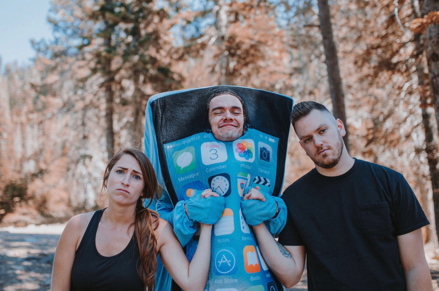 Image of two friends holding the hands of a guy in a iPhone costume