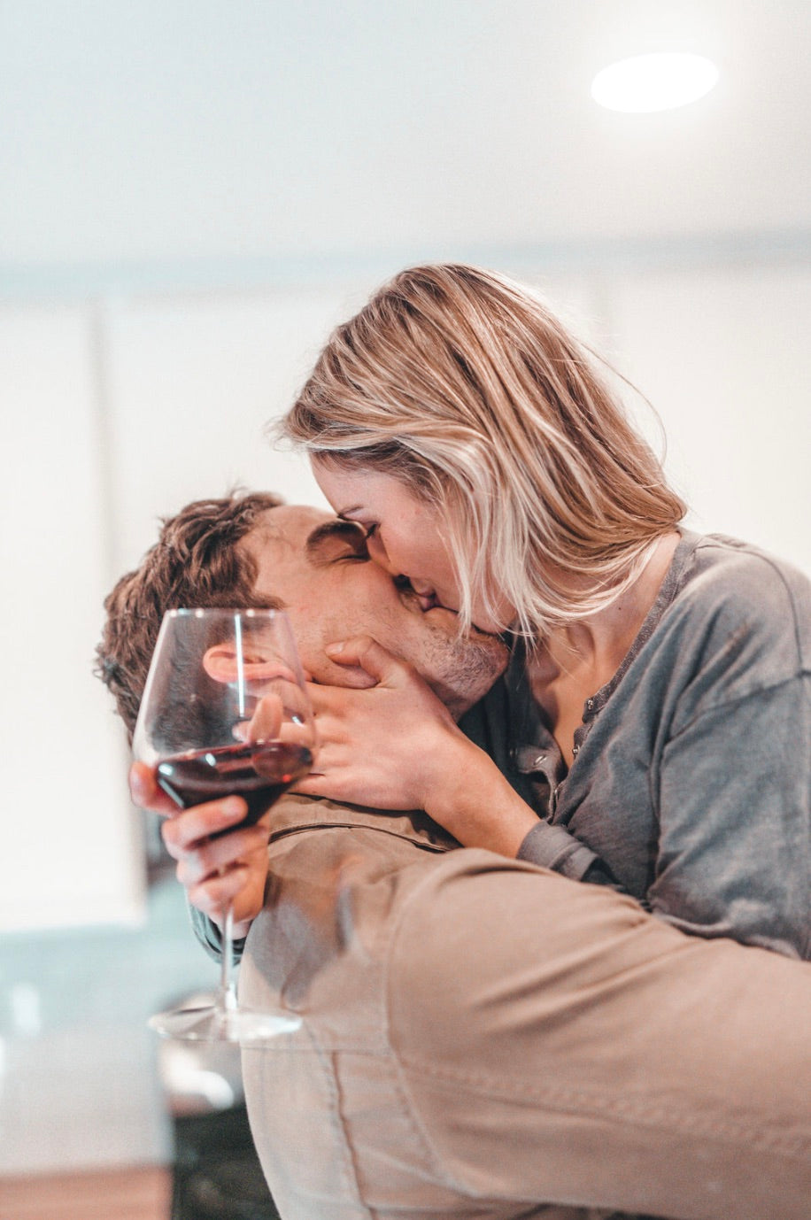 How to bring back the spark in a relationship; Couple sharing a kiss as the girl holds a glass of wine