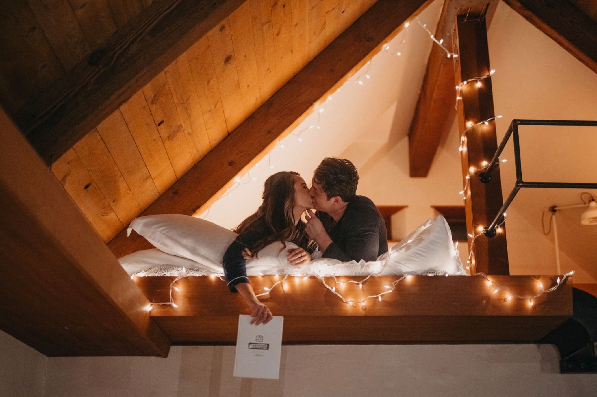 Couple kissing each other as the girl holds a copy of The Adventure Challenge Couple's Edition in her hand