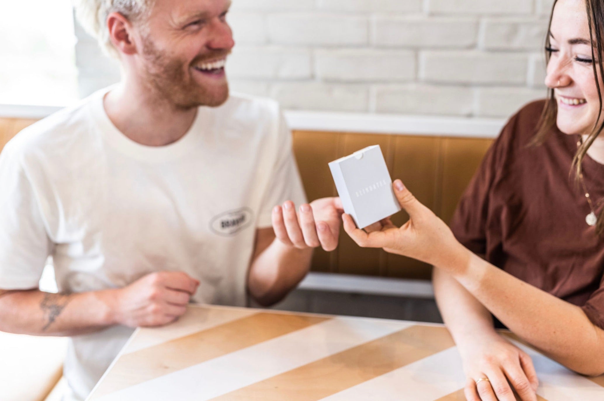 Girlfriend giving her boyfriend a gift box as they smile at each other