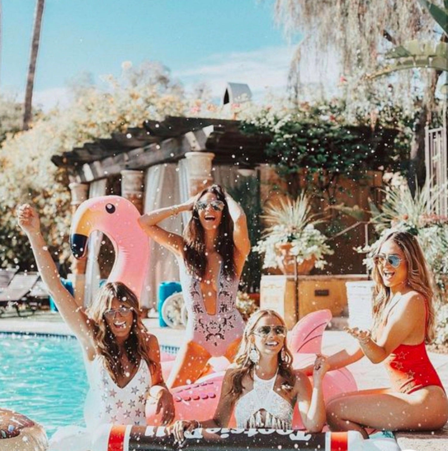 Four girls achieving their best friend goals by having fun at the pool with trendy flamingo and tootsie roll floaties