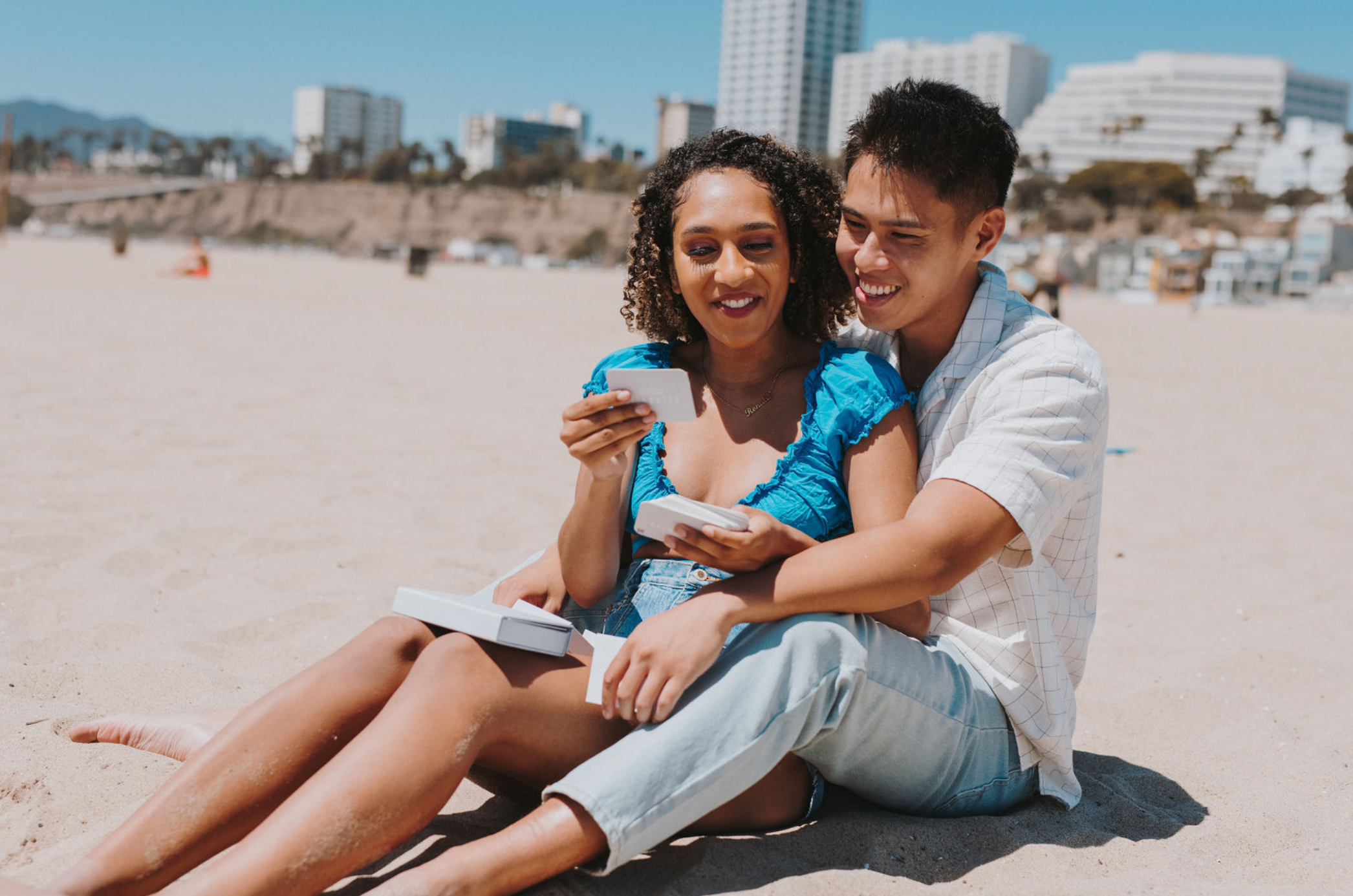 Couple smiling and playing with Connection Cards on the beach