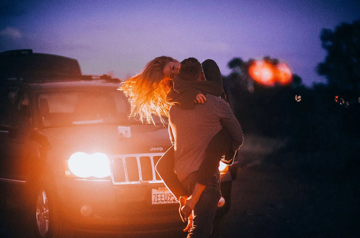 How Adventure Date Ideas Will Transform Your Relationship. Boyfriend carrying girlfriend in his arms as she smiles in front of their Jeep.