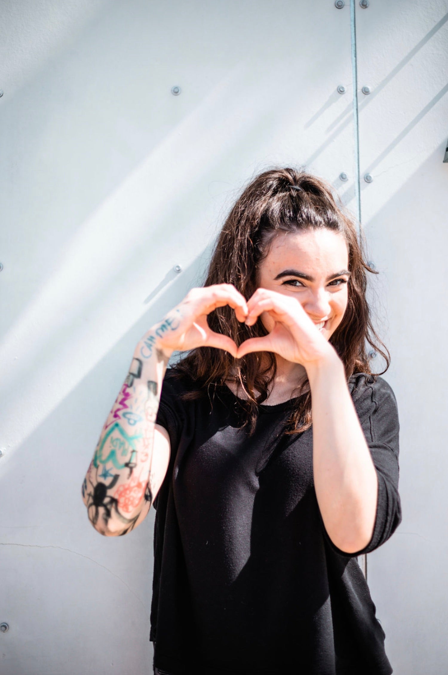 Image of a woman making a heart sign with her hands as she smiles about how to ask a girl out