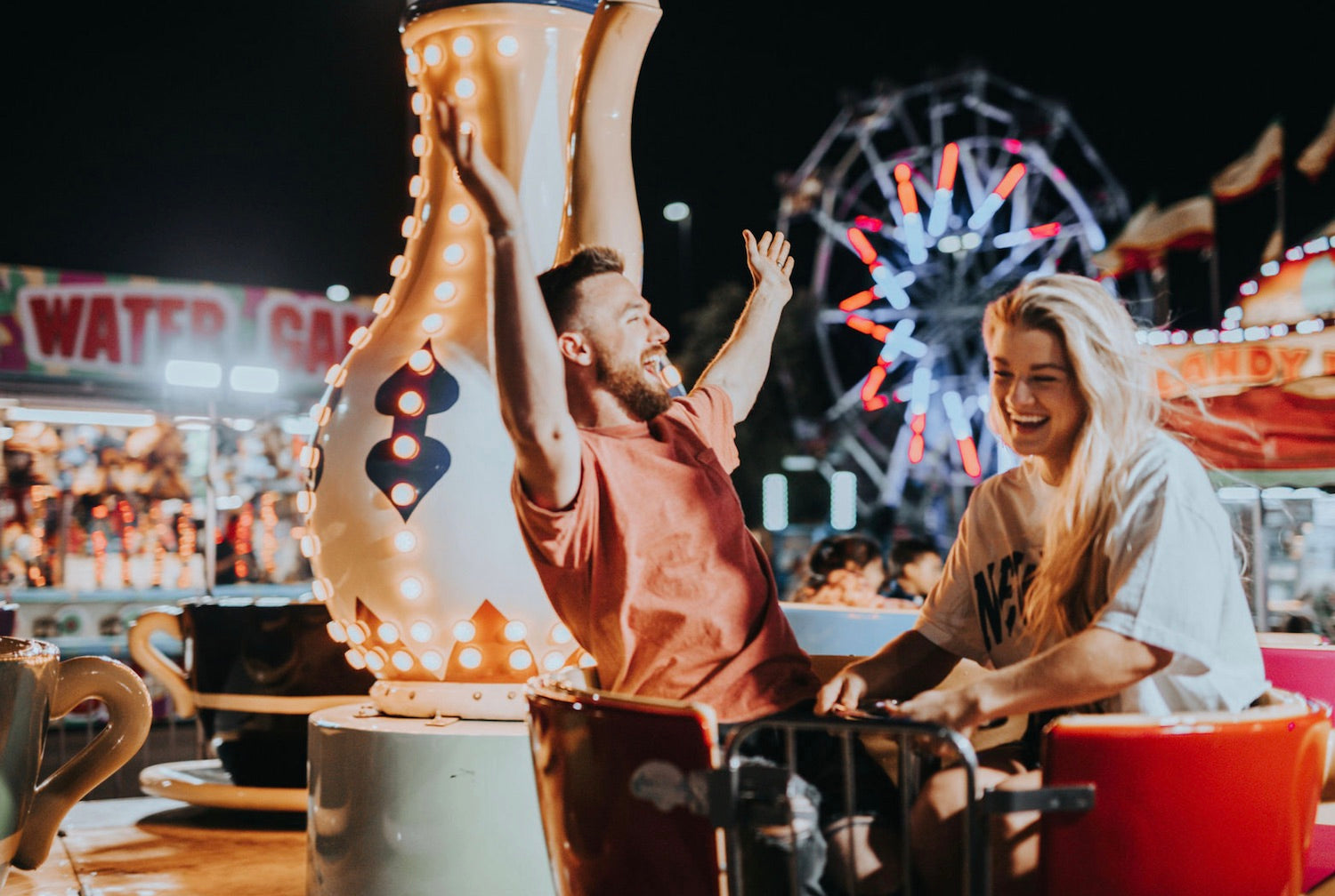Image of a couple laughing while riding a carnival ride that was on their summer bucket list as a couple.