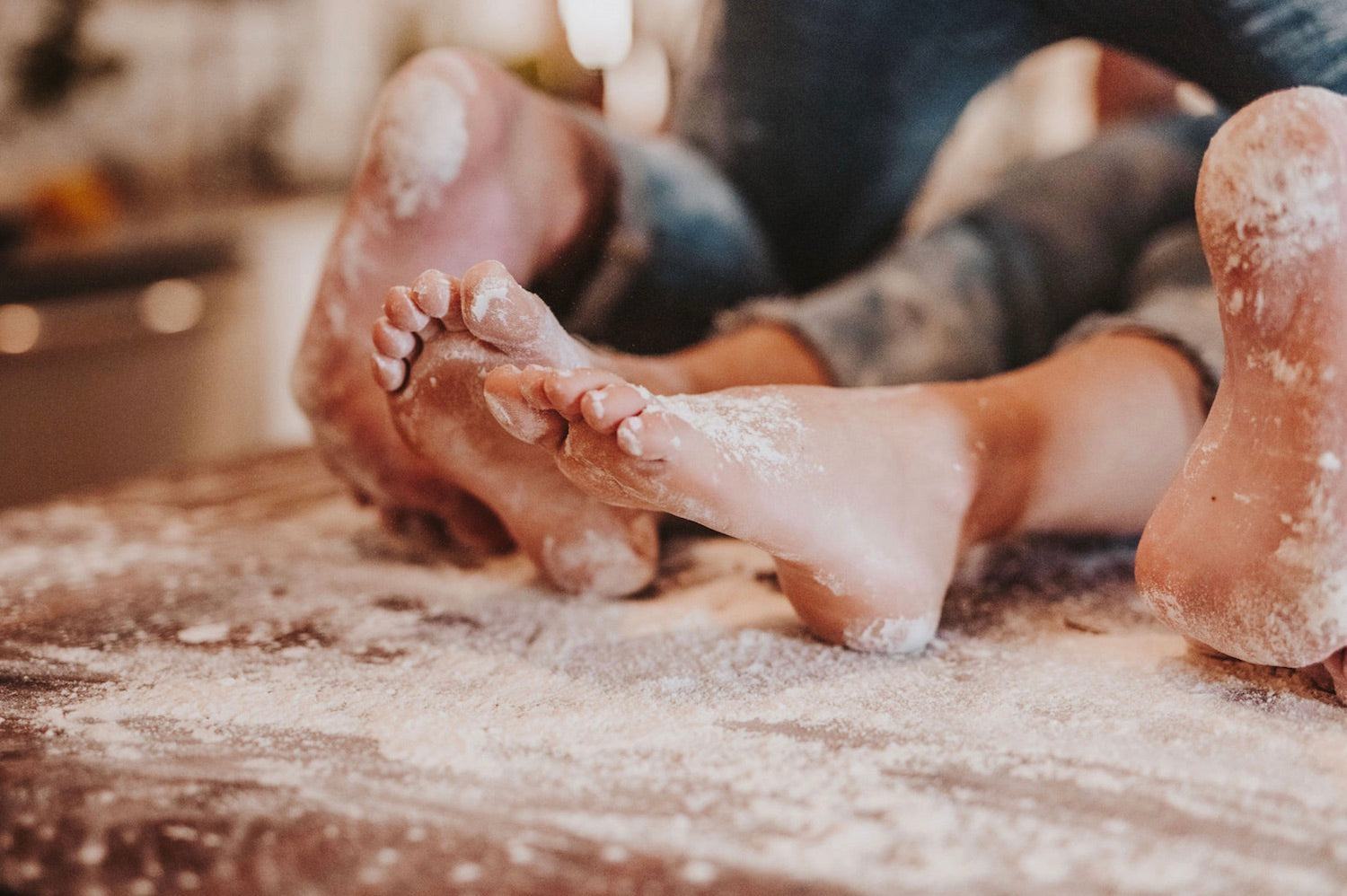 10 Romantic and Fun Sex Ideas for Couples Celebrating an Anniversary. Close-up shot of couple's feet on the kitchen table covered in flour.