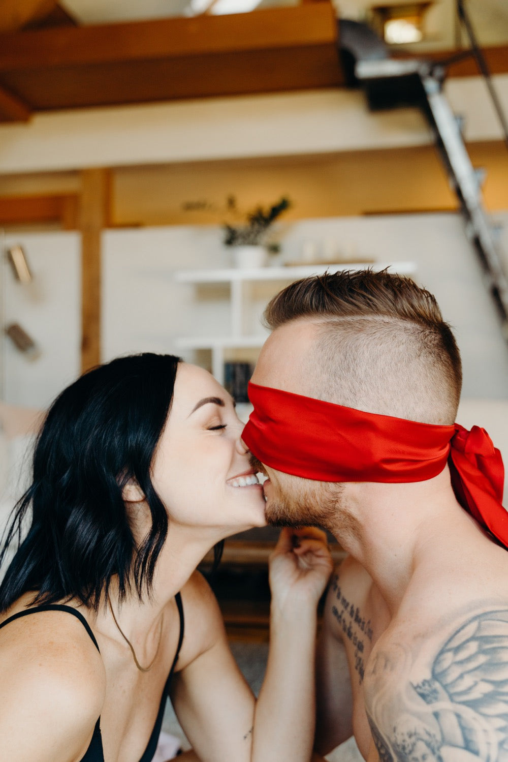 The 15 Best Sex Games for Couples to Spice Up the Romance: Couple smiling with the guy wearing a red blindfold