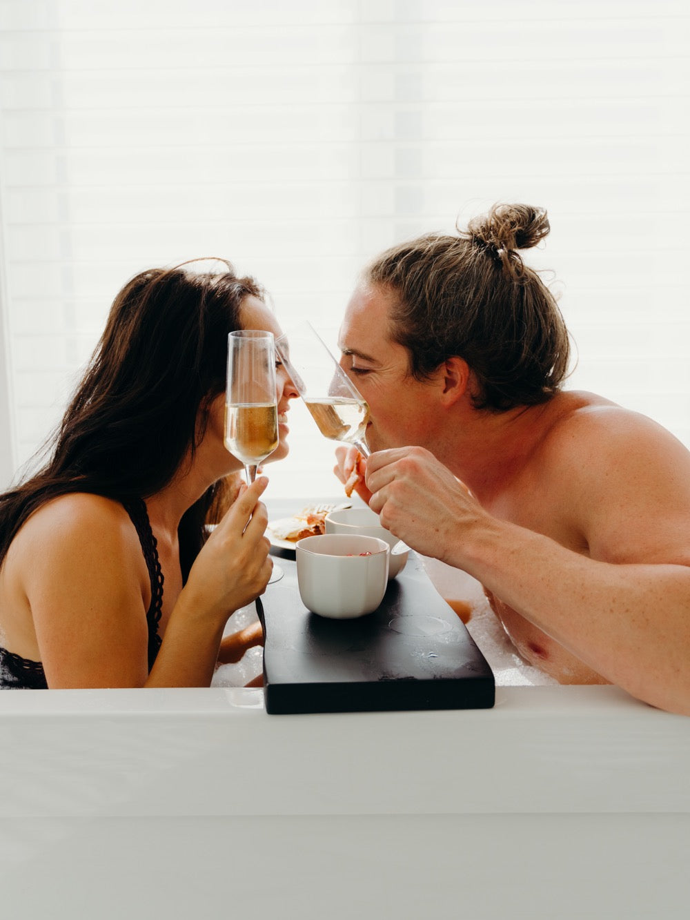 50 Items for Your Sexual Bucket List: Couple sharing food and champagne in bath tub.
