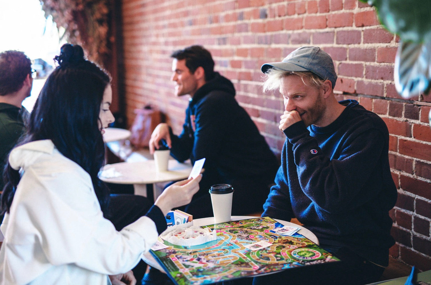 A couple sit at a coffee shop playing a board game together