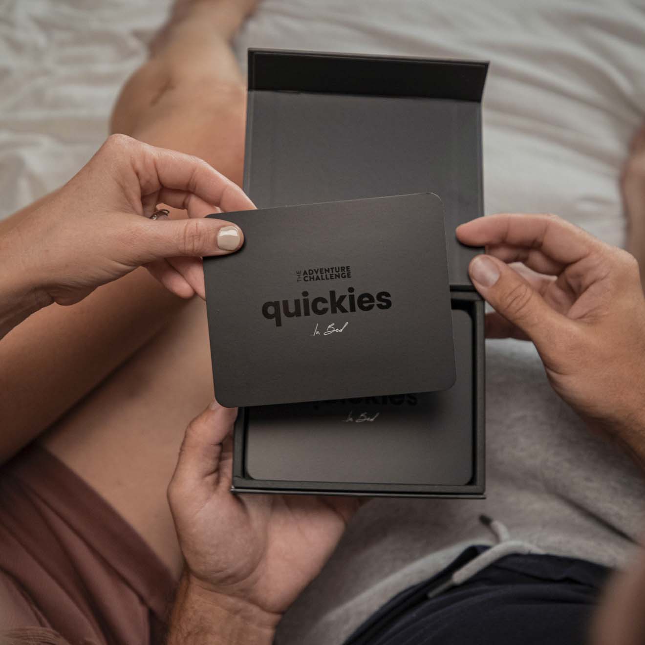 How to spice up your love life in 30 minutes: Quickies from The Adventure Challenge. A couple holding the cards in bed!